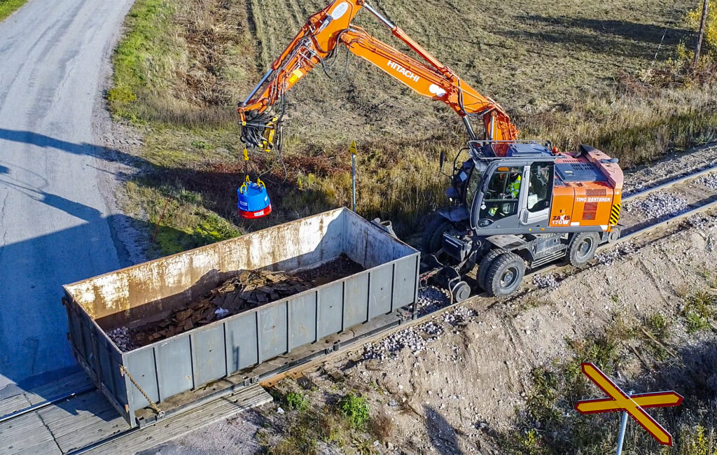 HMAG PRO hydraulic magnet loading railway metal parts into a container with an excavator
