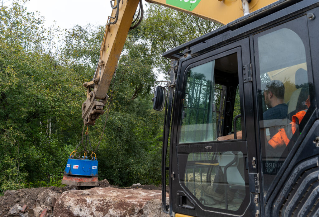 HMAG PRO Hydraulic Magnet with chain mounting attached to an excavator collecting metal on a worksite